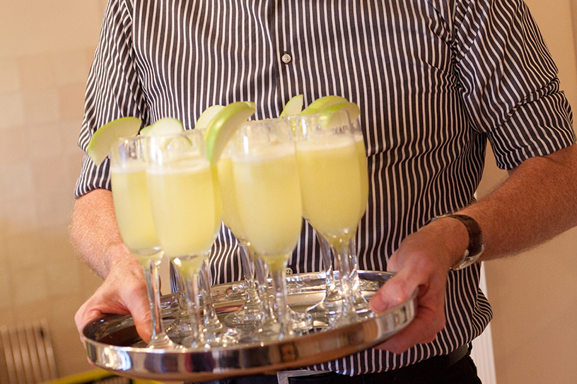Iemand serveert frisse drankjes met schijfjes appel aan de glaasjes